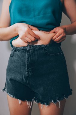 Şişman kadın, şişko, obez kadın el ele tutuşan ölçü bandıyla göbek yağı, kadın diyeti yaşam tarzı konsepti