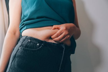 Şişman kadın, şişko, obez kadın el ele tutuşan ölçü bandıyla göbek yağı, kadın diyeti yaşam tarzı konsepti