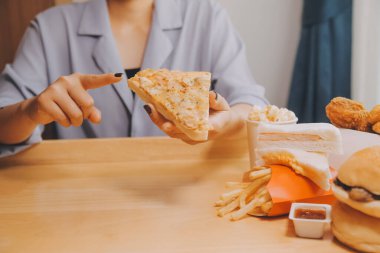 Restoranda pizza dilimi tutan bir kadın resmi.