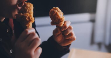 Odaklan kadın. Elin kızarmış tavuğu yemek için tutuyor. Fast food konsepti olan bir kız.