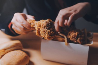 Odaklan kadın. Elin kızarmış tavuğu yemek için tutuyor. Fast food konsepti olan bir kız.