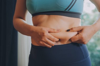 Şişman kadın, şişko, obez kadın el ele tutuşan ölçü bandıyla göbek yağı, kadın diyeti yaşam tarzı konsepti