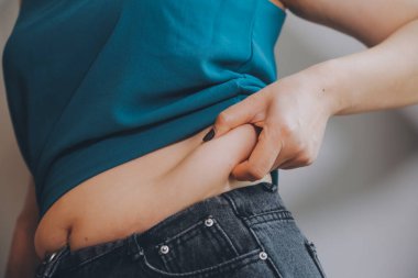 Şişman kadın, şişko, obez kadın el ele tutuşan ölçü bandıyla göbek yağı, kadın diyeti yaşam tarzı konsepti