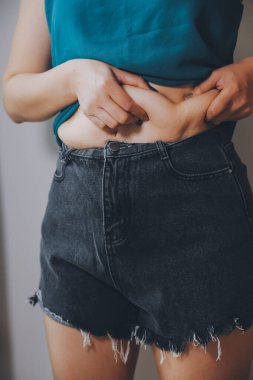 Şişman kadın, şişko, obez kadın el ele tutuşan ölçü bandıyla göbek yağı, kadın diyeti yaşam tarzı konsepti