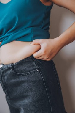 Şişman kadın, şişko, obez kadın el ele tutuşan ölçü bandıyla göbek yağı, kadın diyeti yaşam tarzı konsepti