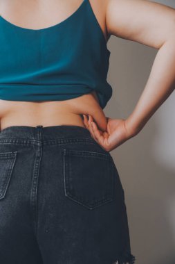 Şişman kadın, şişko, obez kadın el ele tutuşan ölçü bandıyla göbek yağı, kadın diyeti yaşam tarzı konsepti