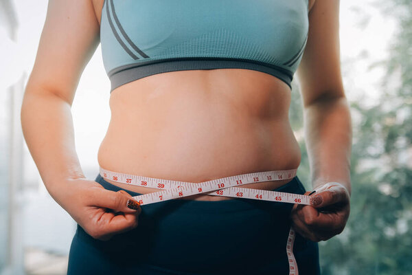 толстая женщина, жирный живот, пухлый, толстая женщина рука держит избыточный жир живота с помощью ленты, женщина диета образ жизни