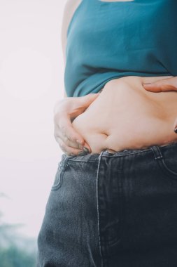 Şişman kadın, şişko, obez kadın el ele tutuşan ölçü bandıyla göbek yağı, kadın diyeti yaşam tarzı konsepti