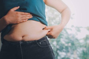 Şişman kadın, şişko, obez kadın el ele tutuşan ölçü bandıyla göbek yağı, kadın diyeti yaşam tarzı konsepti