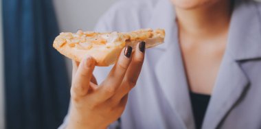 Restoranda pizza dilimi tutan bir kadın resmi.
