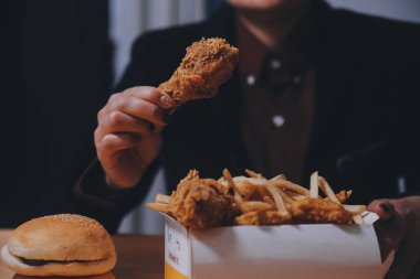 Odaklan kadın. Elin kızarmış tavuğu yemek için tutuyor. Fast food konsepti olan bir kız.