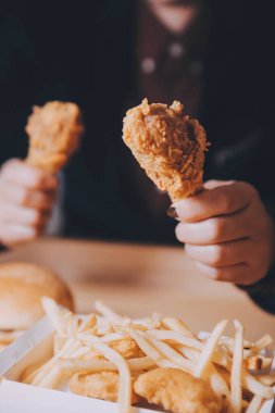 Odaklan kadın. Elin kızarmış tavuğu yemek için tutuyor. Fast food konsepti olan bir kız.