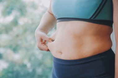 Şişman kadın, şişko, obez kadın el ele tutuşan ölçü bandıyla göbek yağı, kadın diyeti yaşam tarzı konsepti