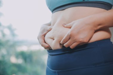 Şişman kadın, şişko, obez kadın el ele tutuşan ölçü bandıyla göbek yağı, kadın diyeti yaşam tarzı konsepti