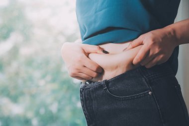 Şişman kadın, şişko, obez kadın el ele tutuşan ölçü bandıyla göbek yağı, kadın diyeti yaşam tarzı konsepti