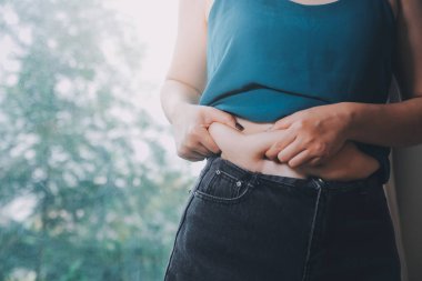 Şişman kadın, şişko, obez kadın el ele tutuşan ölçü bandıyla göbek yağı, kadın diyeti yaşam tarzı konsepti