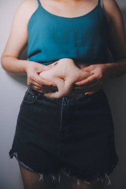 Şişman kadın, şişko, obez kadın el ele tutuşan ölçü bandıyla göbek yağı, kadın diyeti yaşam tarzı konsepti