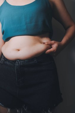 Şişman kadın, şişko, obez kadın el ele tutuşan ölçü bandıyla göbek yağı, kadın diyeti yaşam tarzı konsepti