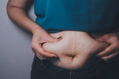 Şişman kadın, şişko, obez kadın el ele tutuşan ölçü bandıyla göbek yağı, kadın diyeti yaşam tarzı konsepti