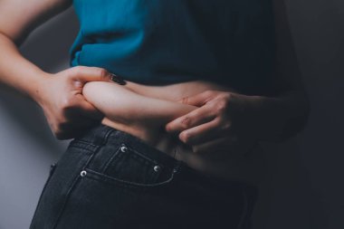 Şişman kadın, şişko, obez kadın el ele tutuşan ölçü bandıyla göbek yağı, kadın diyeti yaşam tarzı konsepti