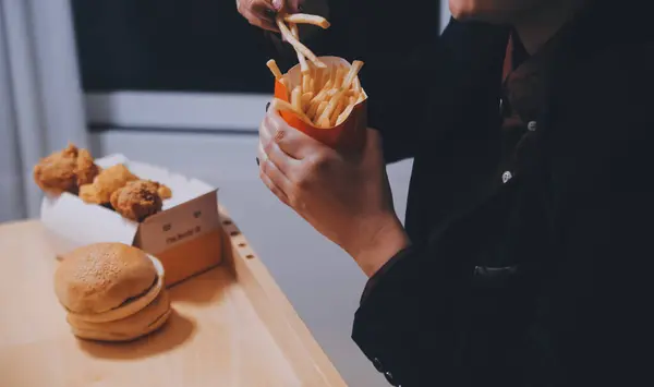 stock image Asian woman holding french fries and eating happily in restaurant