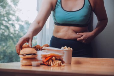 Yemek ya da değil. Burger bakarak cheerless tombul kadın yemek ya da değil düşünme