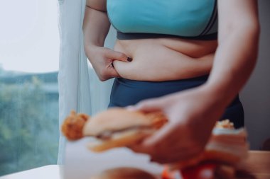 Yemek ya da değil. Burger bakarak cheerless tombul kadın yemek ya da değil düşünme