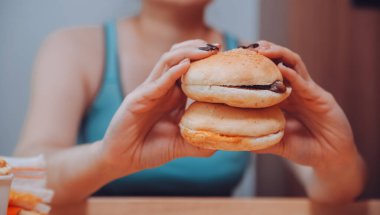 Binge eating disorder concept with woman eating fast food burger, fired chicken , donuts and desserts clipart