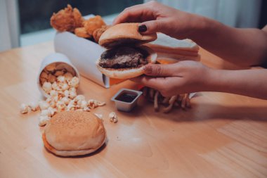 lokanta, insanlar ve sağlıksız beslenme kavramı - yakın çekim kadın elinde hamburger ya da çizburger tutarak