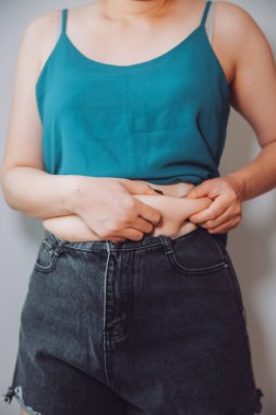 Şişman kadın, şişko, obez kadın el ele tutuşan ölçü bandıyla göbek yağı, kadın diyeti yaşam tarzı konsepti