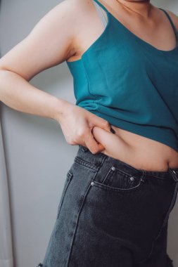 Şişman kadın, şişko, obez kadın el ele tutuşan ölçü bandıyla göbek yağı, kadın diyeti yaşam tarzı konsepti