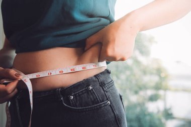 Şişman kadın, şişko, obez kadın el ele tutuşan ölçü bandıyla göbek yağı, kadın diyeti yaşam tarzı konsepti