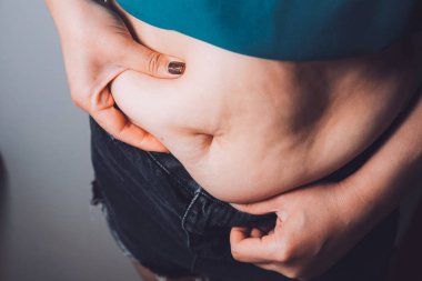 Şişman kadın, şişko, obez kadın el ele tutuşan ölçü bandıyla göbek yağı, kadın diyeti yaşam tarzı konsepti