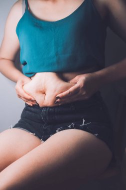 Şişman kadın, şişko, obez kadın el ele tutuşan ölçü bandıyla göbek yağı, kadın diyeti yaşam tarzı konsepti