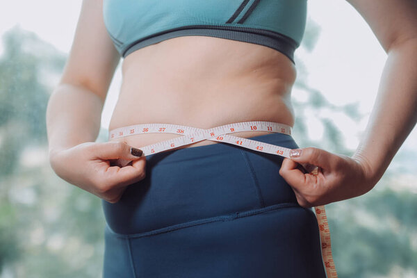 толстая женщина, жирный живот, пухлый, толстая женщина рука держит избыточный жир живота с помощью ленты, женщина диета образ жизни