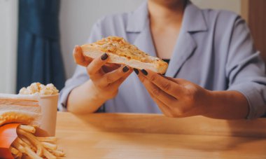 Restoranda pizza dilimi tutan bir kadın resmi.