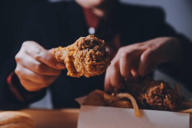 Odaklan kadın. Elin kızarmış tavuğu yemek için tutuyor. Fast food konsepti olan bir kız.