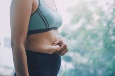 Şişman kadın, şişko, obez kadın el ele tutuşan ölçü bandıyla göbek yağı, kadın diyeti yaşam tarzı konsepti