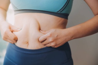 Şişman kadın, şişko, obez kadın el ele tutuşan ölçü bandıyla göbek yağı, kadın diyeti yaşam tarzı konsepti