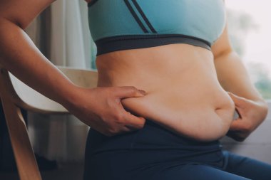 Şişman kadın, şişko, obez kadın el ele tutuşan ölçü bandıyla göbek yağı, kadın diyeti yaşam tarzı konsepti