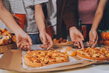 Bir grup genç arkadaş evde pizza ve hazır yemekle parti veriyor.