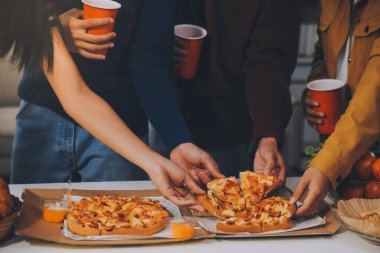 Bir grup genç arkadaş evde pizza ve hazır yemekle parti veriyor.