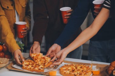 Bir grup genç arkadaş evde pizza ve hazır yemekle parti veriyor.