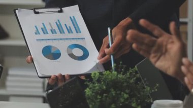 Modern ofiste finansal tablolar ve iş raporlarıyla çalışan bir grup iş adamı