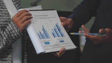 Modern ofiste finansal tablolar ve iş raporlarıyla çalışan bir grup iş adamı
