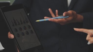 Modern ofiste finansal tablolar ve iş raporlarıyla çalışan bir grup iş adamı