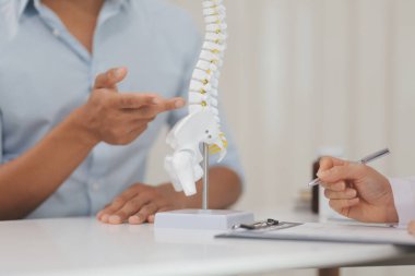 Ortopedistler dijital tablet tutuyor ve mankeni işaret ediyorlar. Osteoporoz, sırt ağrısı, bel, kiropraktik ve sağlık kavramı.