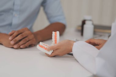 Diş hekimi muayenesi. Diş hekimliği muayenehanesine hasta ziyareti. Diş tellerini açıklamak için takma diş takan kadın diş hekimi hastanın durumu hakkında tavsiye veren ortodonti diş hekimi için kılavuz öneriyor.