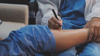 Genç bir Asyalı kadın, bir sağlık sorununu vurgulamak için hastanede ayağını doktora gösteriyor.