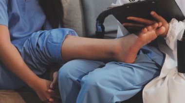 Genç bir Asyalı kadın, bir sağlık sorununu vurgulamak için hastanede ayağını doktora gösteriyor.
